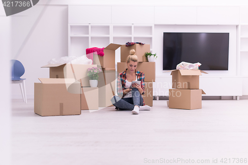 Image of woman with many cardboard boxes sitting on floor