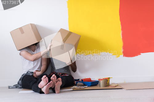 Image of young multiethnic couple playing with cardboard boxes