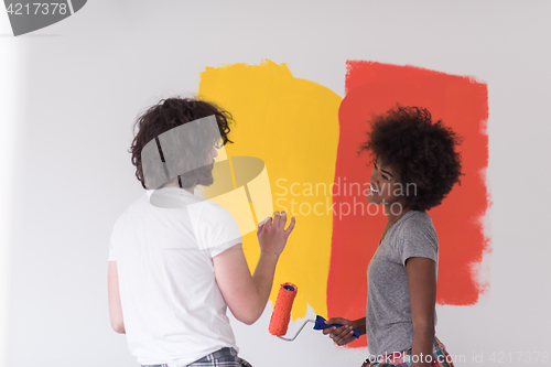 Image of multiethnic couple painting interior wall