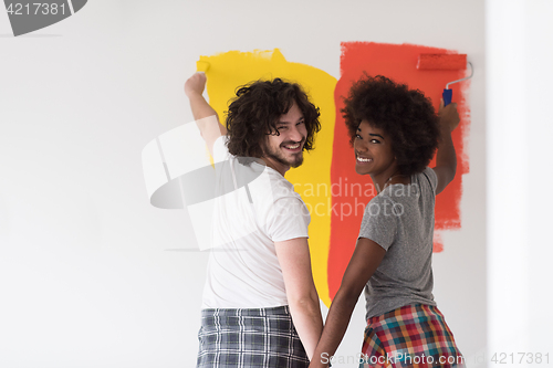 Image of multiethnic couple painting interior wall