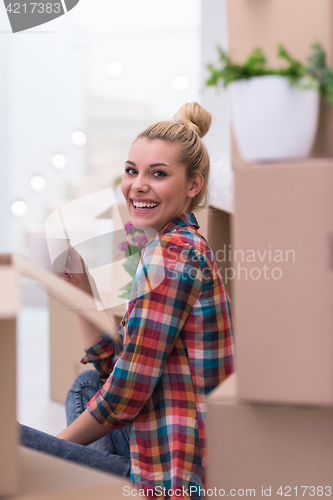 Image of woman with many cardboard boxes sitting on floor