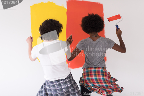 Image of multiethnic couple painting interior wall