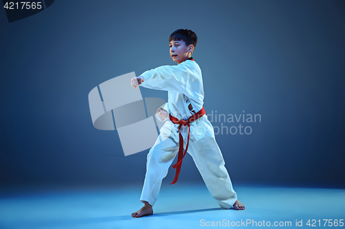 Image of Young boy training karate on blue background