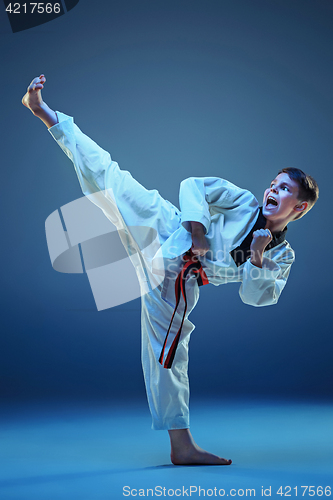 Image of Young boy training karate on blue background