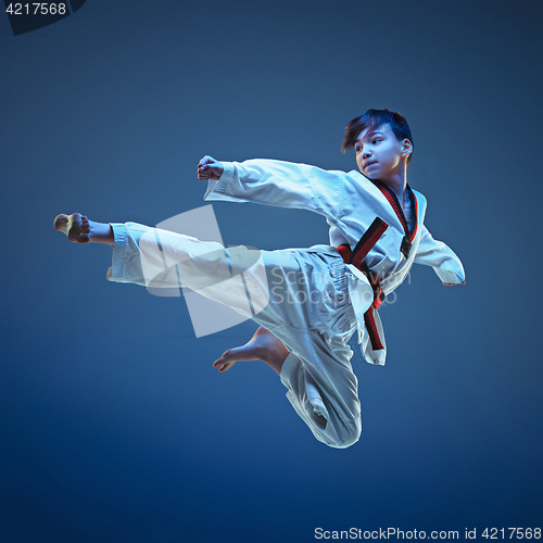 Image of Young boy training karate on blue background