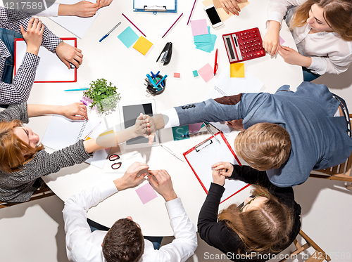 Image of Team sitting behind desk, checking reports, talking. Top View