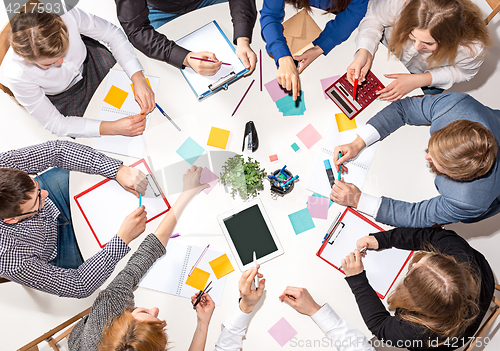 Image of Team sitting behind desk, checking reports, talking. Top View