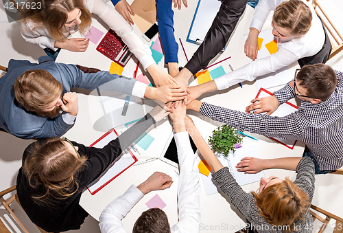 Image of Team sitting behind desk, checking reports, talking. Top View