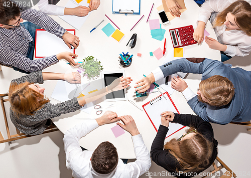 Image of Team sitting behind desk, checking reports, talking. Top View