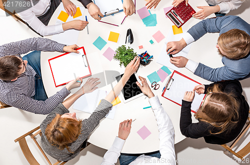 Image of Team sitting behind desk, checking reports, talking. Top View