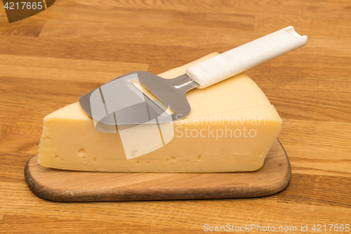 Image of Piece of cheese with a slicer