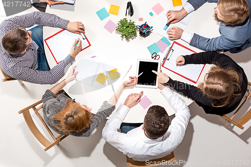 Image of Team sitting behind desk, checking reports, talking. Top View