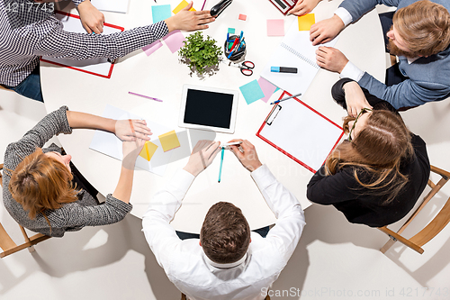 Image of Team sitting behind desk, checking reports, talking. Top View