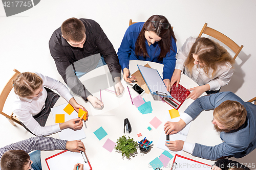 Image of Team sitting behind desk, checking reports, talking. Top View