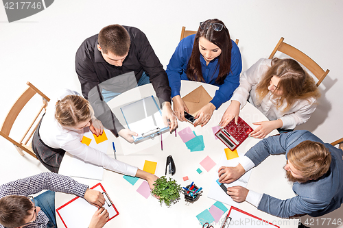 Image of Team sitting behind desk, checking reports, talking. Top View