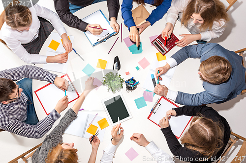 Image of Team sitting behind desk, checking reports, talking. Top View