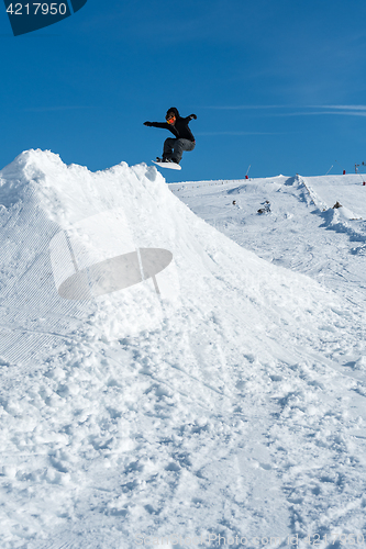 Image of Snowboarder jumping against blue sky