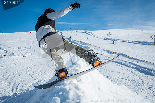 Image of Snowboarder sliding against blue sky