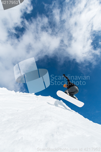 Image of Snowboarder jumping against blue sky