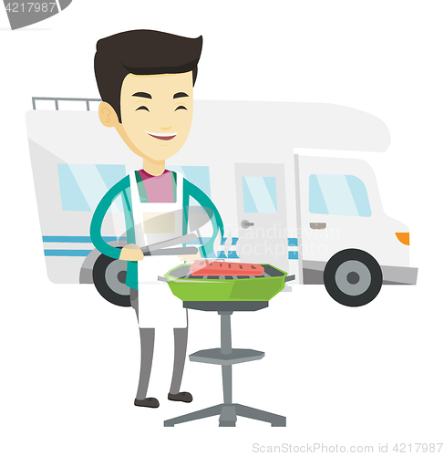 Image of Man having barbecue in front of camper van.