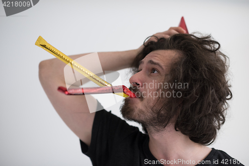 Image of Portrait of a man in party hat blowing in whistle