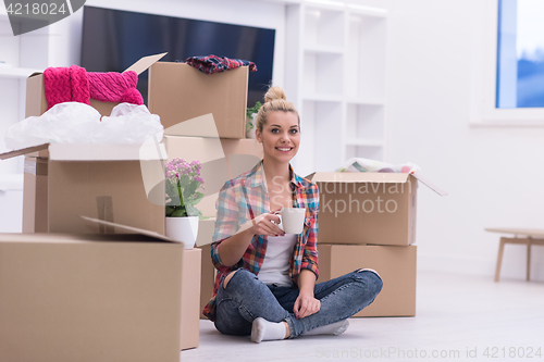 Image of woman with many cardboard boxes sitting on floor