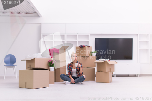 Image of woman with many cardboard boxes sitting on floor