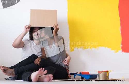 Image of young multiethnic couple playing with cardboard boxes