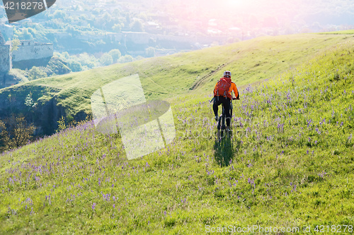 Image of Young man traveler riding on bicycle with red backpack