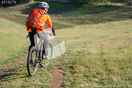 Image of Young man traveler riding on bicycle with red backpack