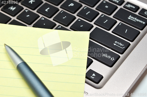 Image of Notepad and pen on black keyboard