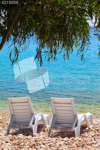 Image of Two deck chairs on beach in sun day