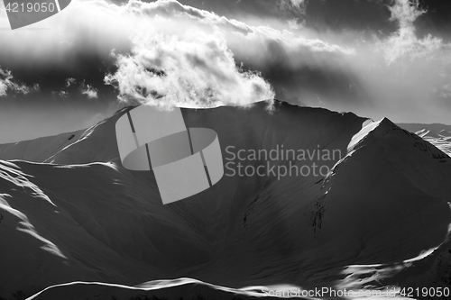 Image of Black and white mountains in sunset with sunlit clouds