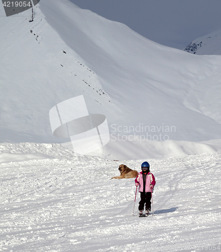 Image of Little skier on ski slope at sun winter day and gray sky before 