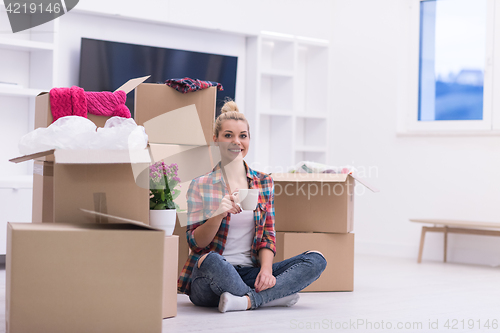 Image of woman with many cardboard boxes sitting on floor