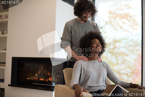 Image of multiethnic couple hugging in front of fireplace