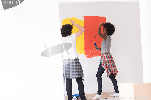 Image of multiethnic couple painting interior wall