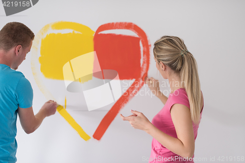 Image of couple are painting a heart on the wall