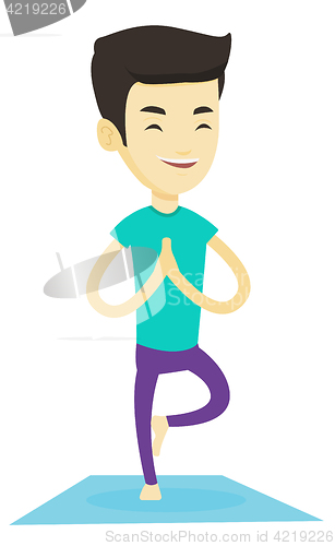 Image of Young man practicing yoga tree pose.