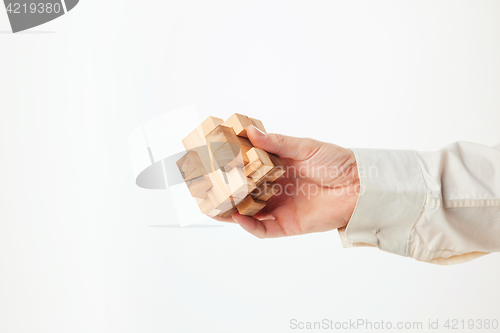 Image of Man\'s hands holding wooden puzzle.