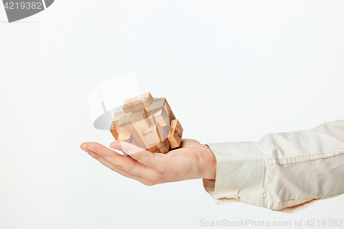 Image of Man\'s hands holding wooden puzzle.