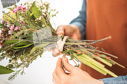 Image of Florist at work: the female hands of woman making fashion modern bouquet of different flowers