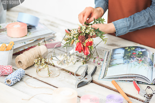 Image of Florist at work: the female hands of woman making fashion modern bouquet of different flowers