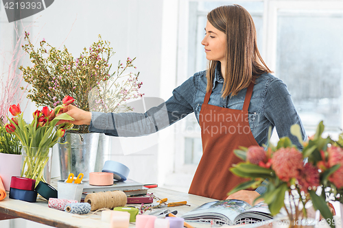 Image of Florist at work: the young girl making fashion modern bouquet of different flowers