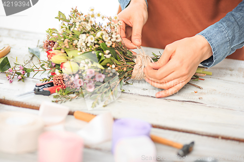 Image of Florist at work: the female hands of woman making fashion modern bouquet of different flowers