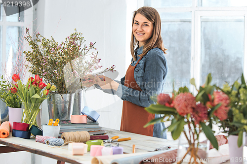 Image of Florist at work: the young girl making fashion modern bouquet of different flowers