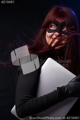 Image of Burglar in mask holds laptop