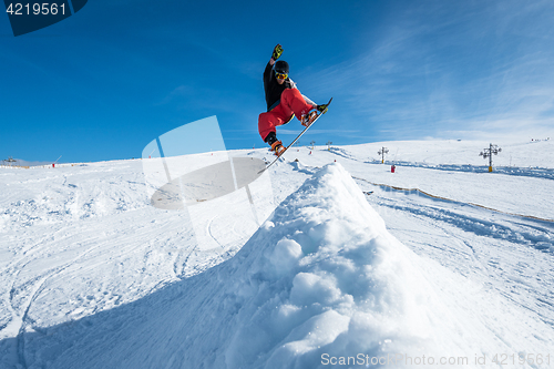 Image of Snowboarder jumping against blue sky