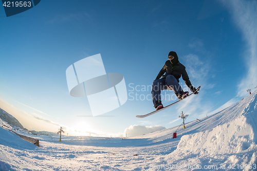 Image of Snowboarder jumping against blue sky