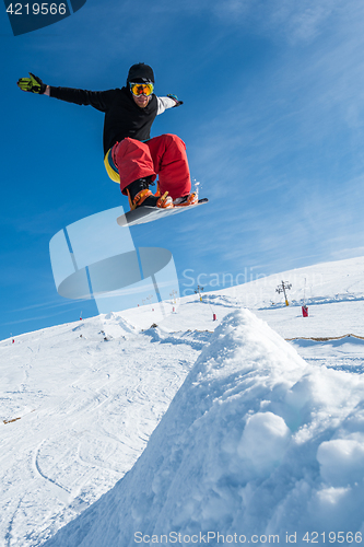 Image of Snowboarder jumping against blue sky